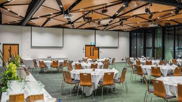 A conference room with round tables, chairs, and a projector screen.