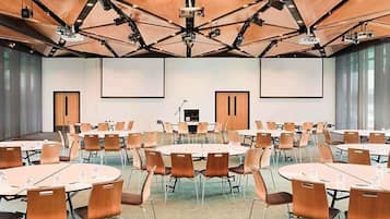 Une salle de conférence dotée de plusieurs tables et de chaises, ainsi que de projecteurs et d’un pupitre.
