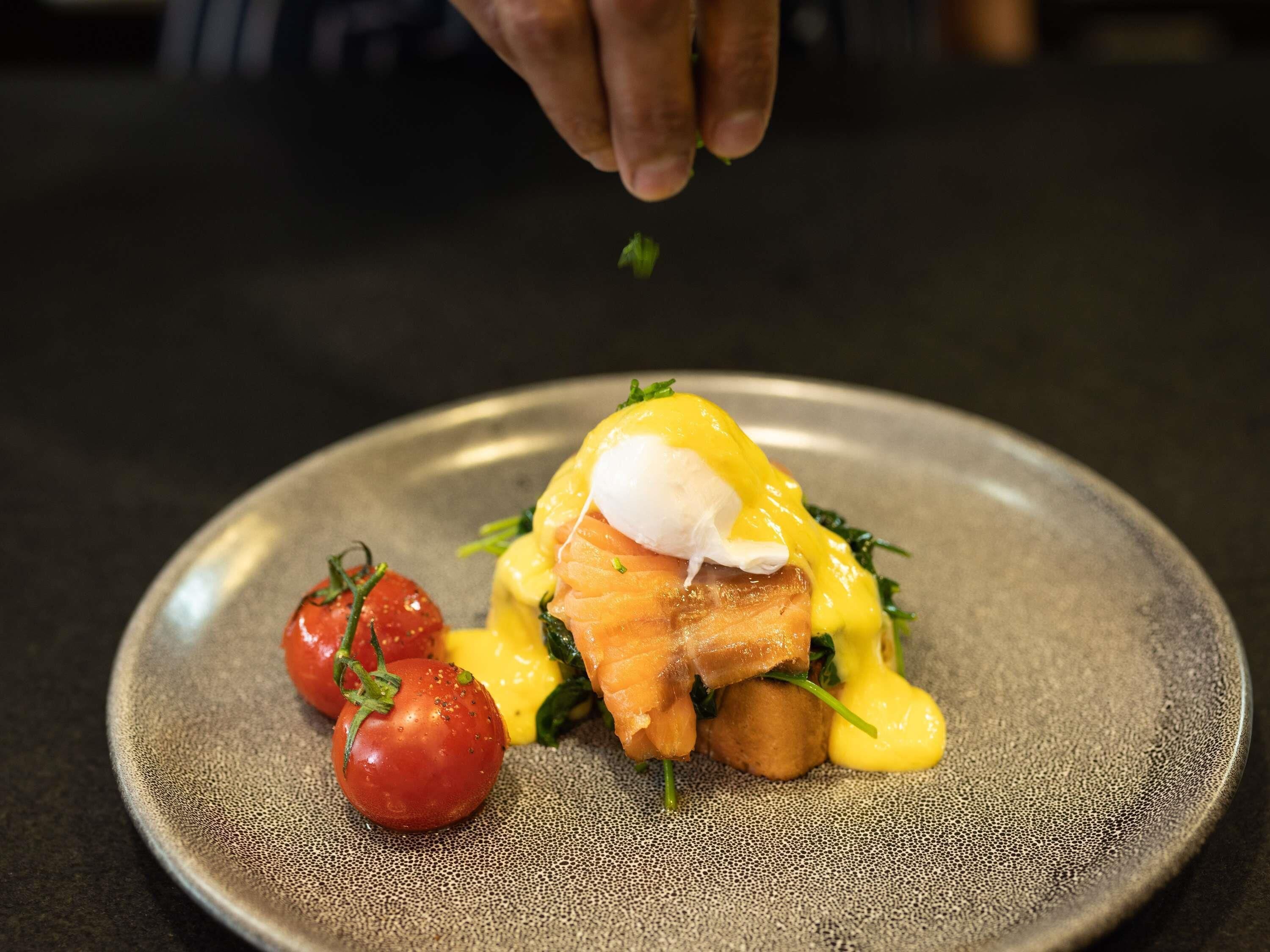 A plate with a poached egg, smoked salmon, and hollandaise sauce, garnished with a sprig of parsley.