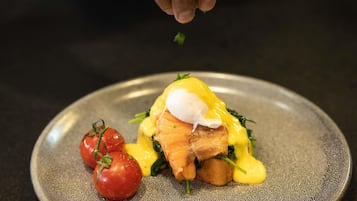 A plate with a poached egg, smoked salmon, and hollandaise sauce, garnished with a sprig of parsley.