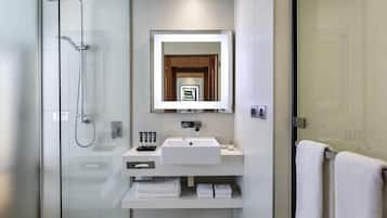 A modern bathroom with a glass-enclosed shower, a white sink, and a mirror above it.