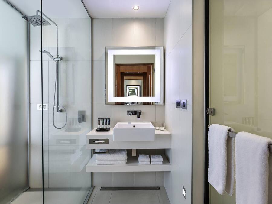 A modern bathroom with a glass-enclosed shower, a white sink, and a mirror above it.