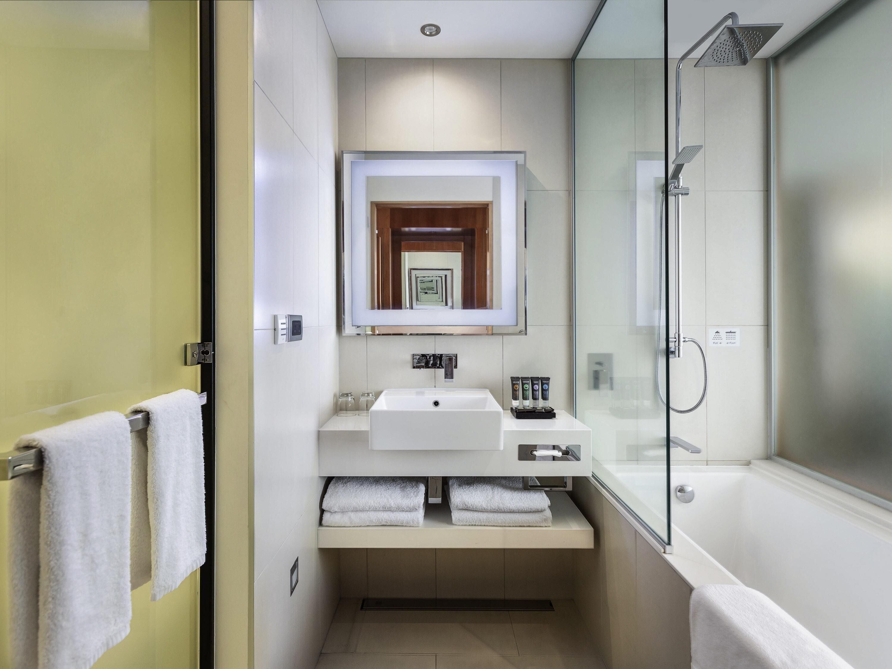 A modern bathroom with a glass shower enclosure, a built-in sink, and a mirror above the vanity.