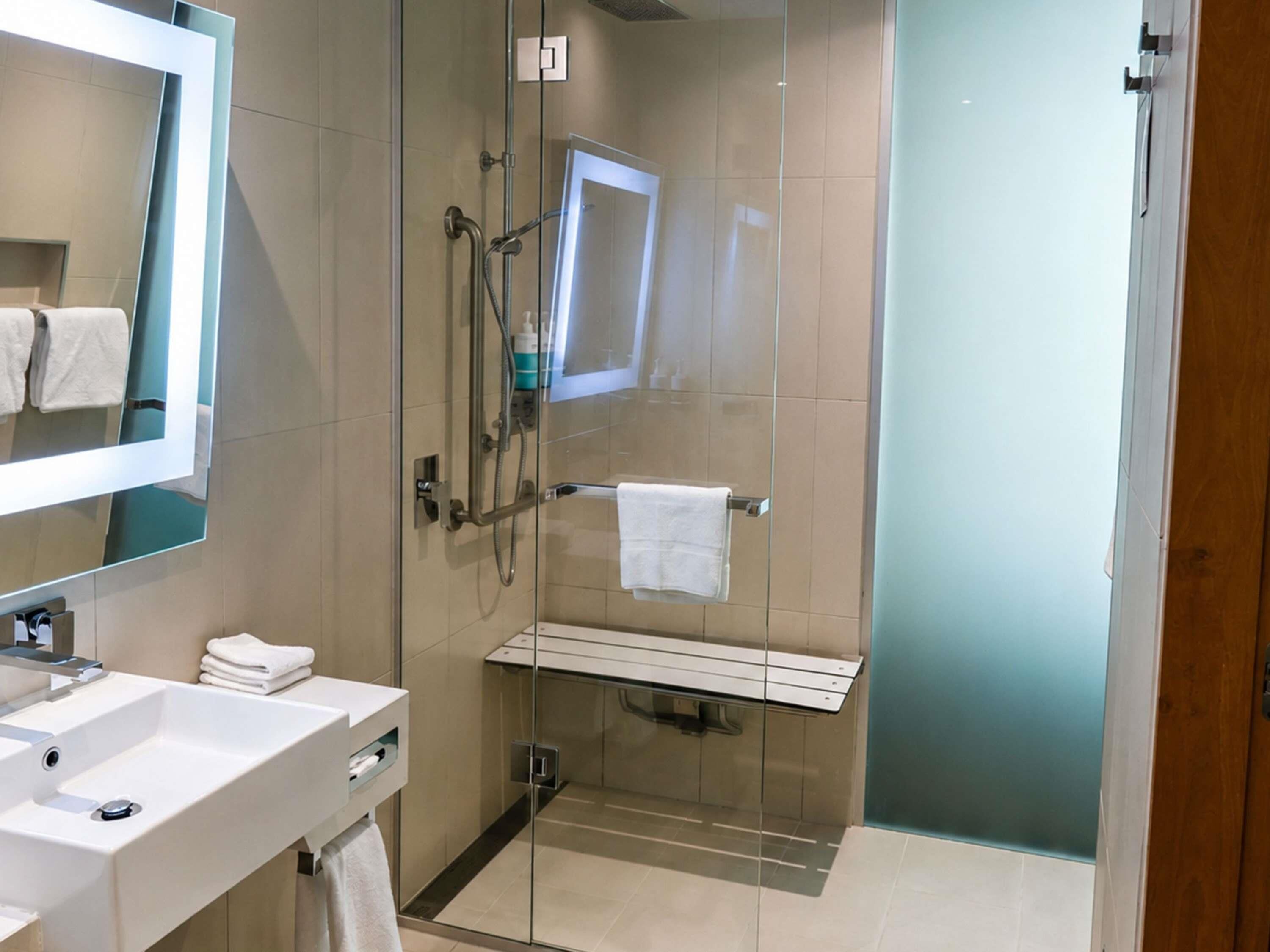 A modern bathroom with a glass-enclosed shower, a white sink, and a mirror.