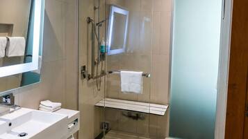 A modern bathroom with a glass-enclosed shower, a white sink, and a mirror.