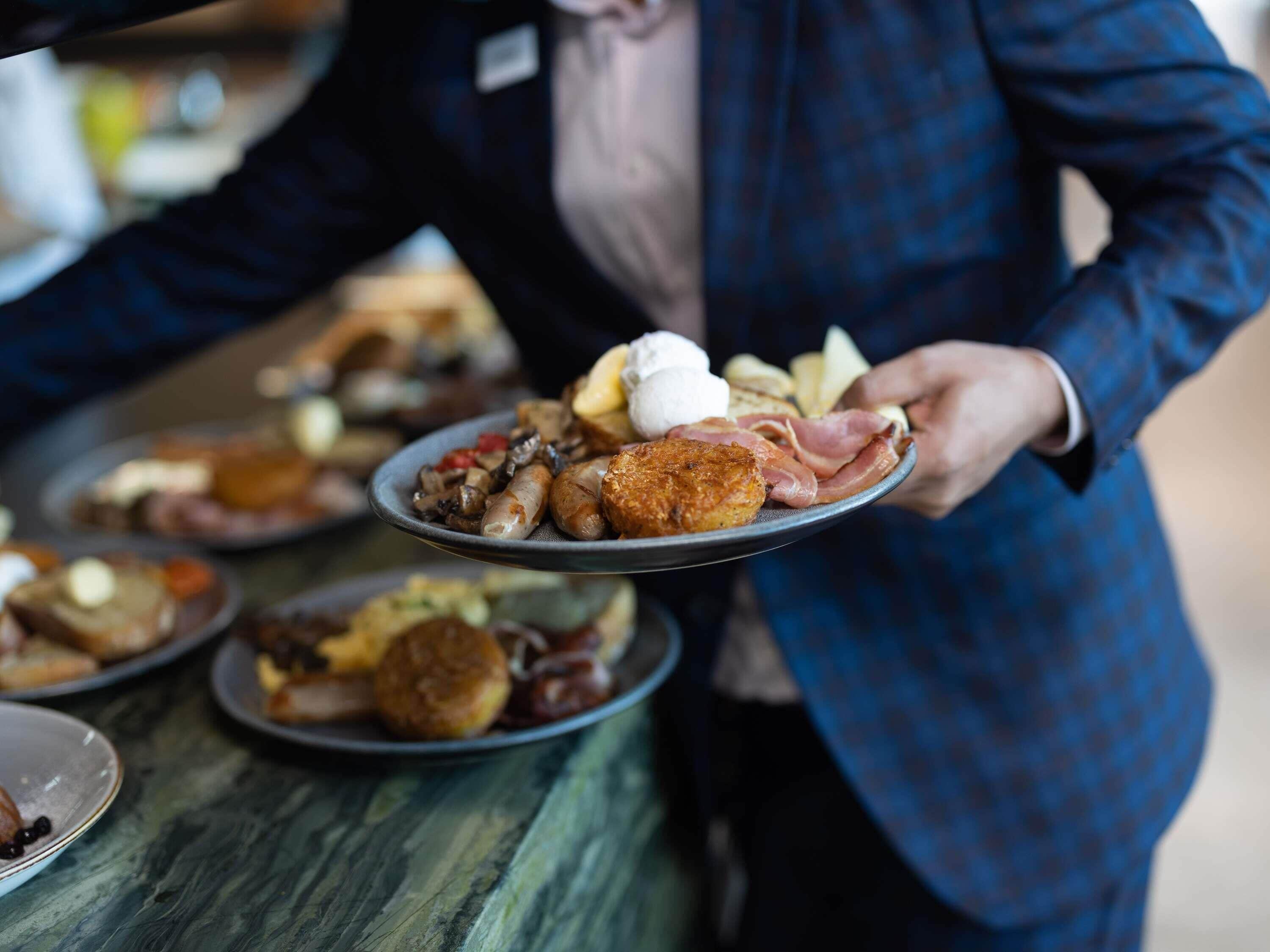 A person serving a plate of food at a buffet.