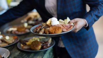 A person serving a plate of food at a buffet.