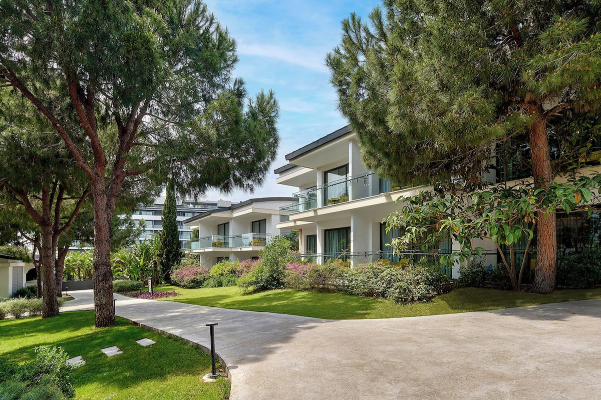 A modern building with a landscaped garden, a clear sky, and a paved walkway.