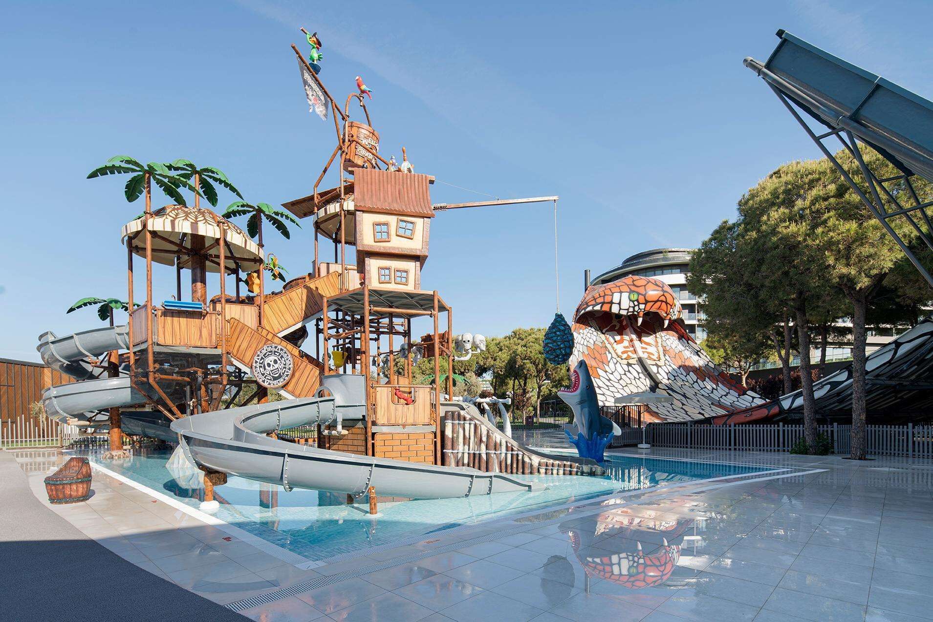 Un parque acuático con una piscina grande, toboganes y una estructura de juego de madera.