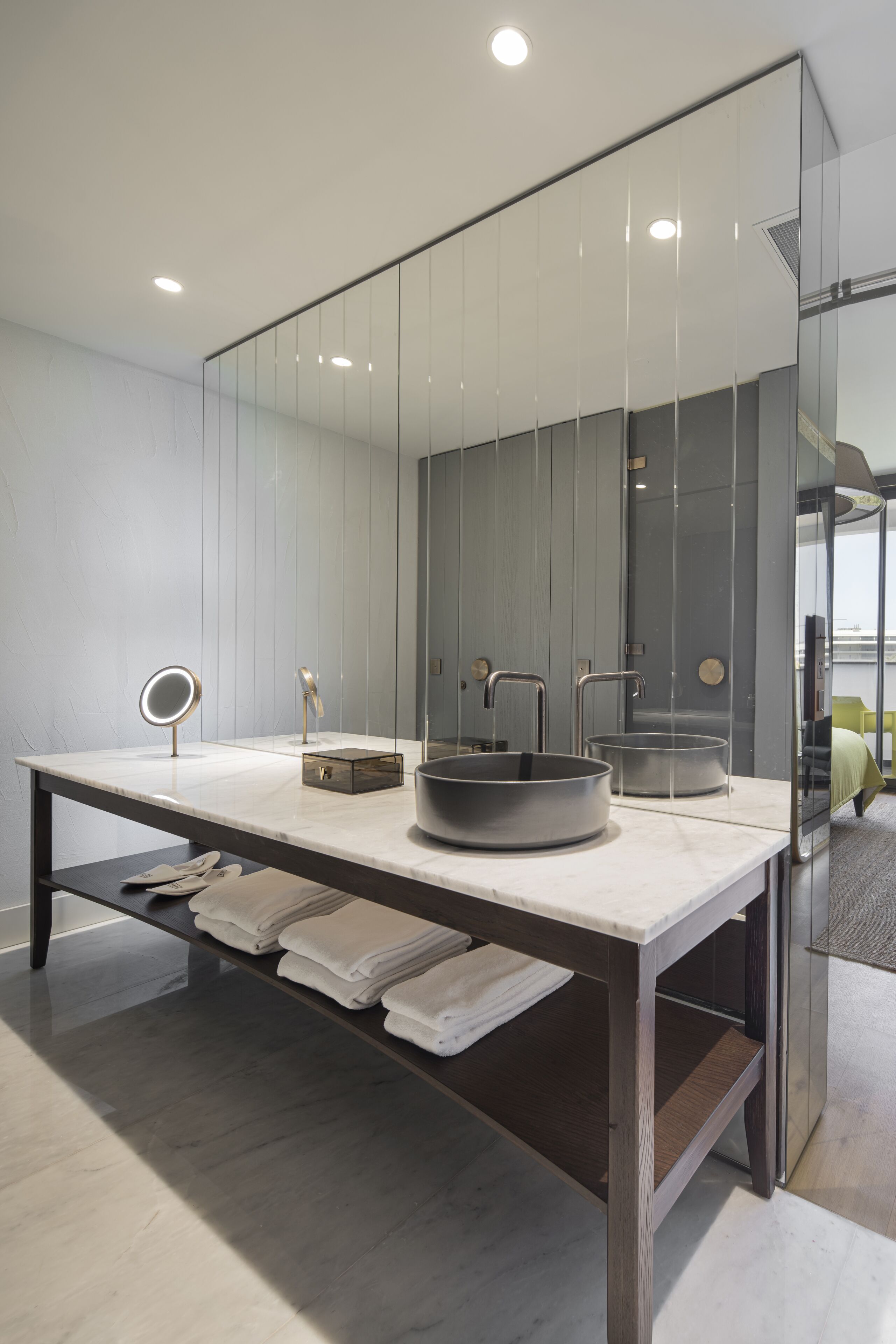 Un baño moderno con un espejo grande, dos lavamanos y un mueble de tocador con toallas.