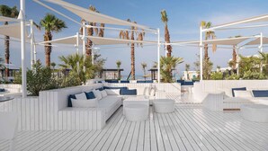 A rooftop lounge area with white wooden flooring, white cushioned seating, and palm trees. - Voyage Belek Golf & Spa (Serik)