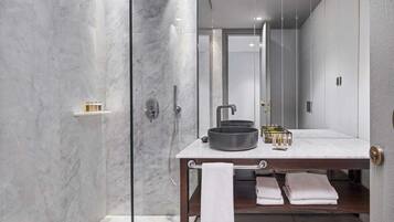 Un baño moderno con ducha envuelta en vidrio, tocador de mármol y un perchero para toallas.