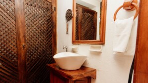 A bathroom with a wooden vanity, a white sink, a mirror, and a towel rack.