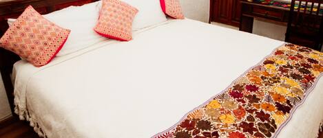 Una cama con una colcha blanca y un edredón floral de colores.