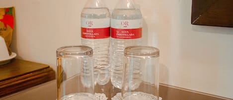 Dos botellas de agua y dos frascos de vidrio con copitos de encaje sobre una mesa.