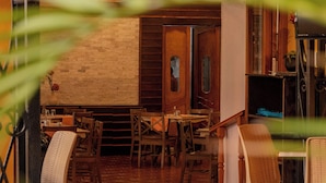Una habitación con pared de ladrillo, puerta de madera y una mesa con sillas.