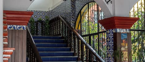 A staircase with blue steps and a wooden handrail, leading to an archway with the text "Restaurante La Terrazza".