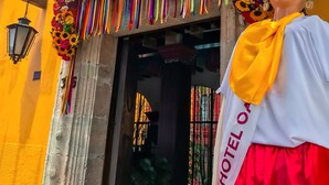 Exterior del Hotel Oaxaca Real, con coloridas decoraciones florales y un letrero sobre la entrada.