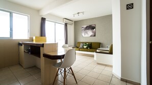 Un espacio habitable compacto con kitchenette, zona de comedor y área de estar con sofá.