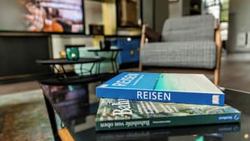 Una pila de libros sobre una mesa de vidrio en una sala de estar.