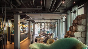 A modern interior with a bar area, seating, and a green sofa. - Motel One Saarbrücken (Saarbrücken)