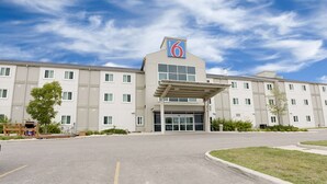 A hotel with a prominent '6' sign, a covered entrance, and a parking lot. - Motel 6 Brandon, MB (Brandon)