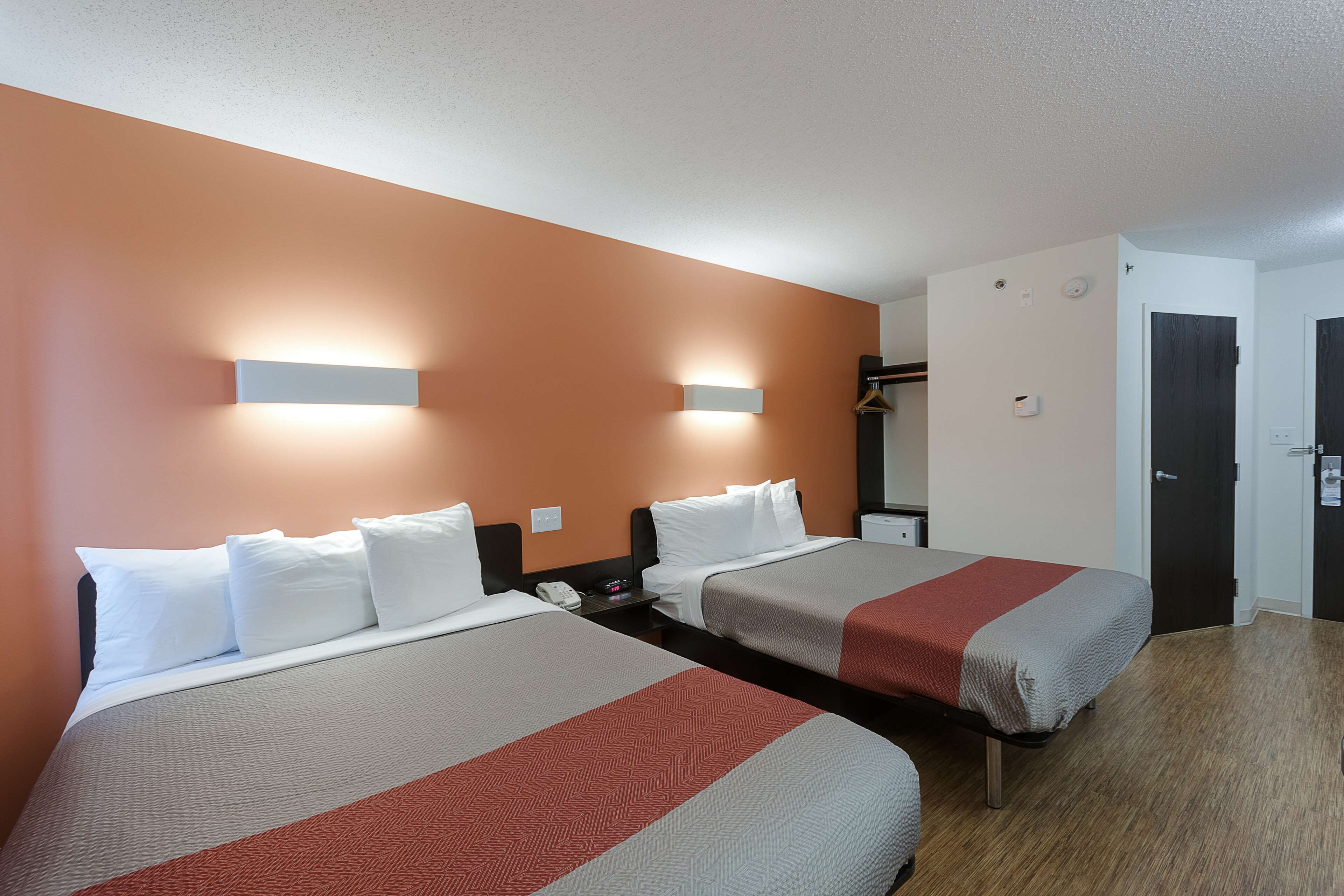 Een hotelkamer met twee bedden, een kledingkast en een deur.