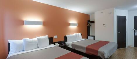 Een hotelkamer met twee bedden, een kledingkast en een deur.