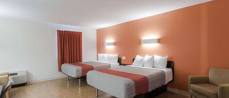 A hotel room with two beds, a chair, a desk, and a window with curtains.