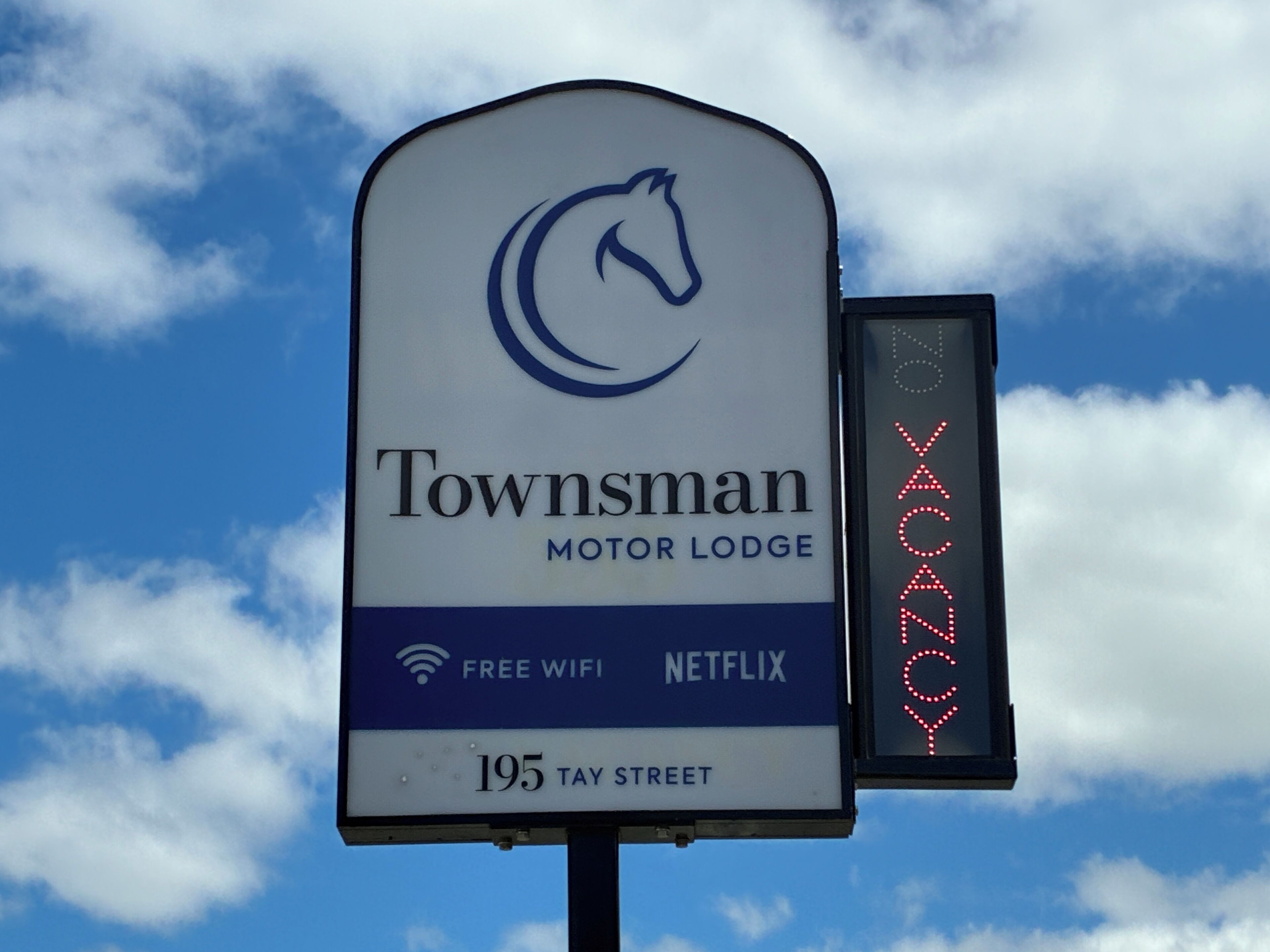 A sign for Townsman Motor Lodge with amenities like free WiFi and Netflix, located at 195 Tay Street.