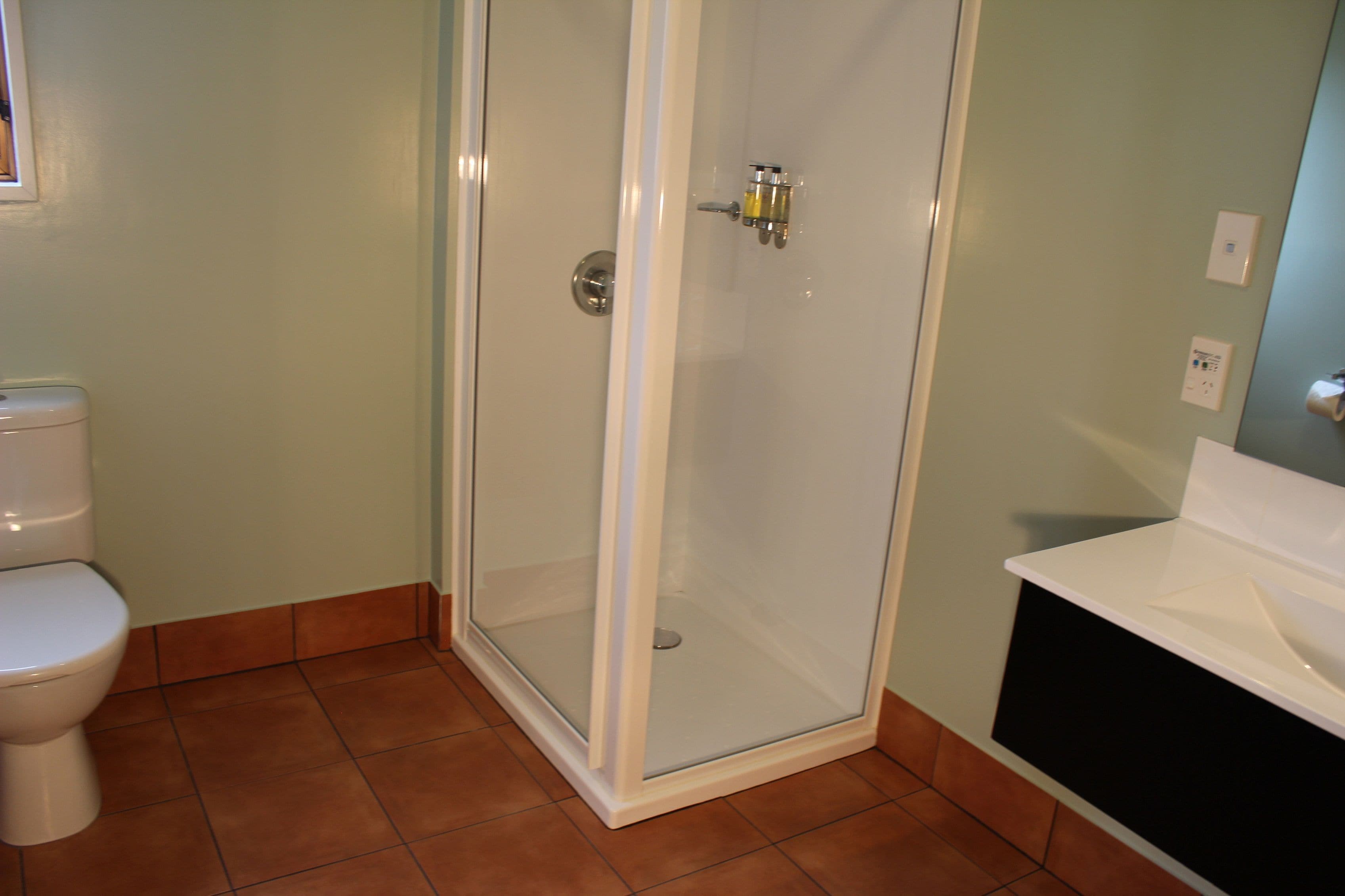 Une salle de bain avec une douche à parois de verre, des toilettes blanches et un lavabo blanc.