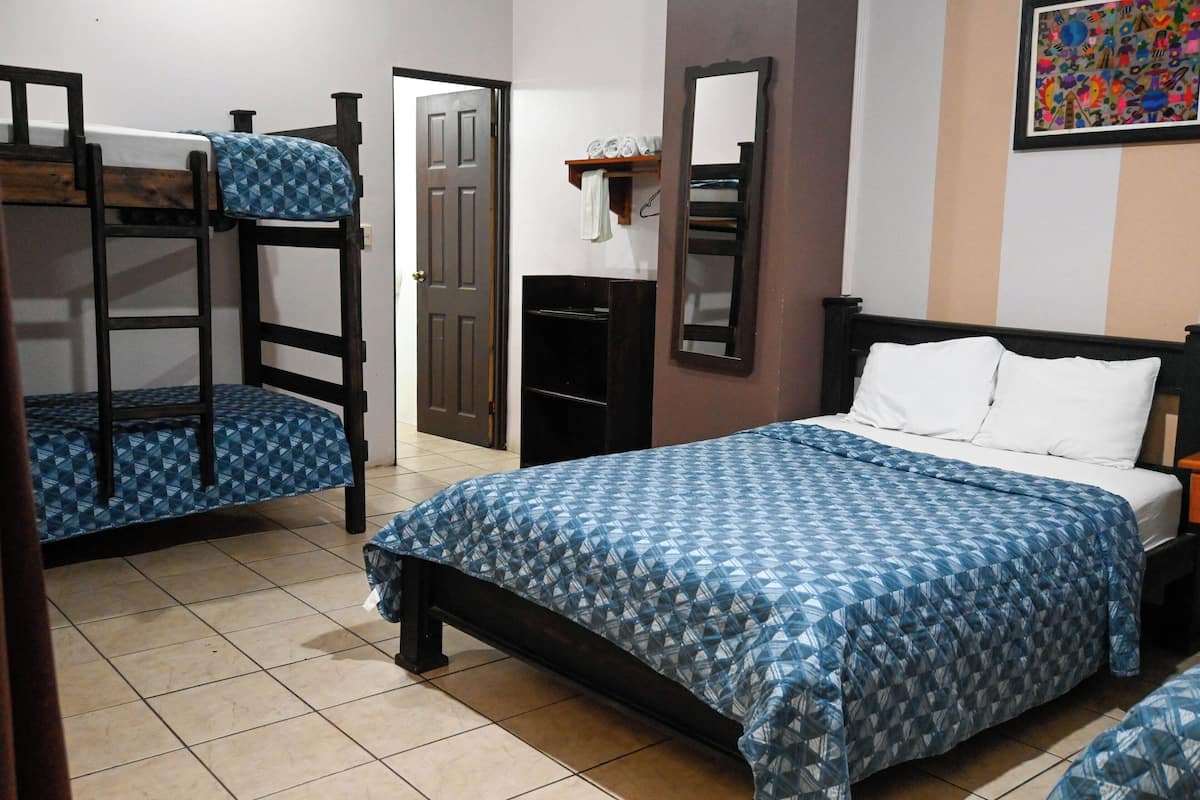 Una habitación con literas, una cama individual, un espejo y un estante con artículos de aseo.