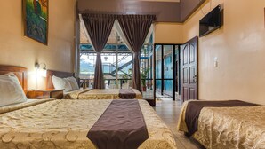 Habitación de hotel con dos camas, un televisor y vista a una escalera que lleva a un balcón.