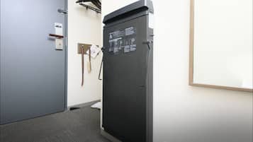 Een hotelkamer met een deur, een zwarte koelkast, een wandhandhouder en een vloerbedekking.