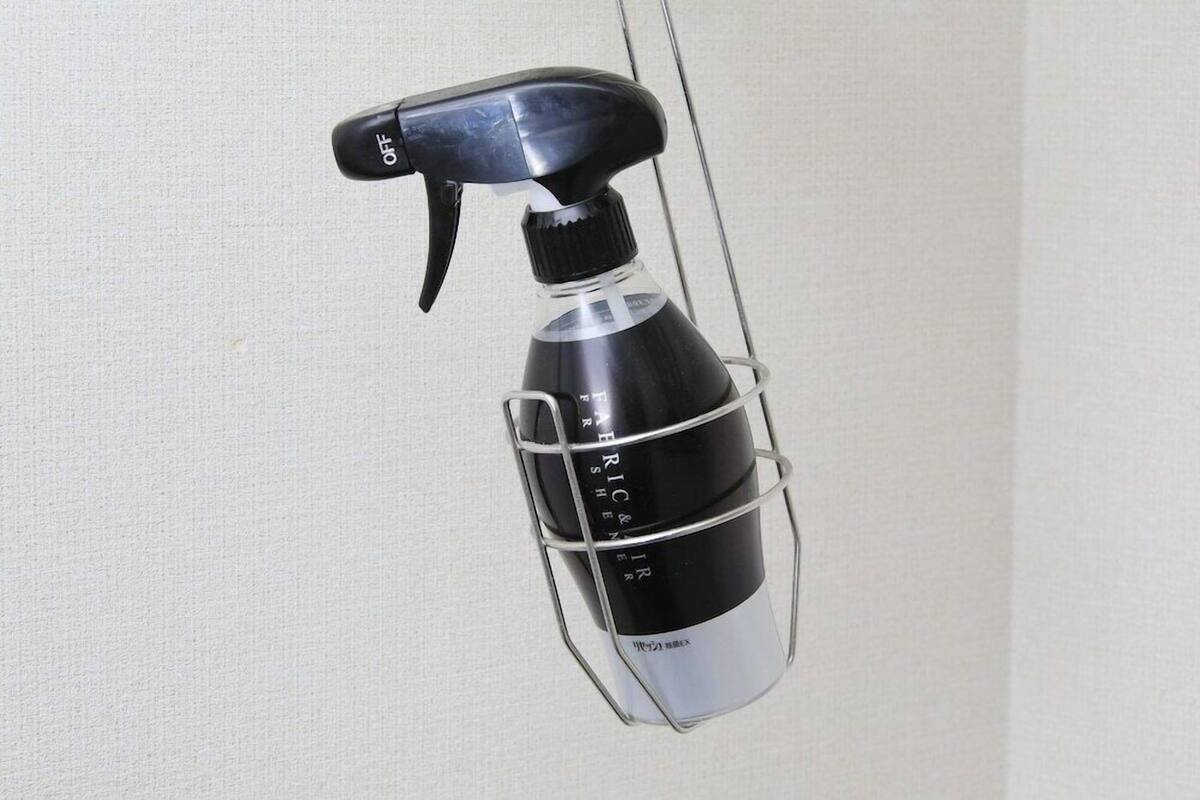 A spray bottle with a black nozzle and a metallic body, hanging from a wire.