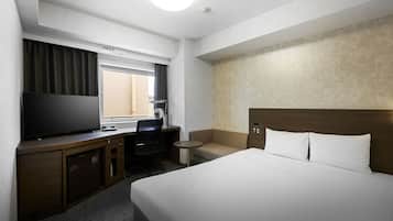 A hotel room with a bed, desk, chair, TV, and a small table.