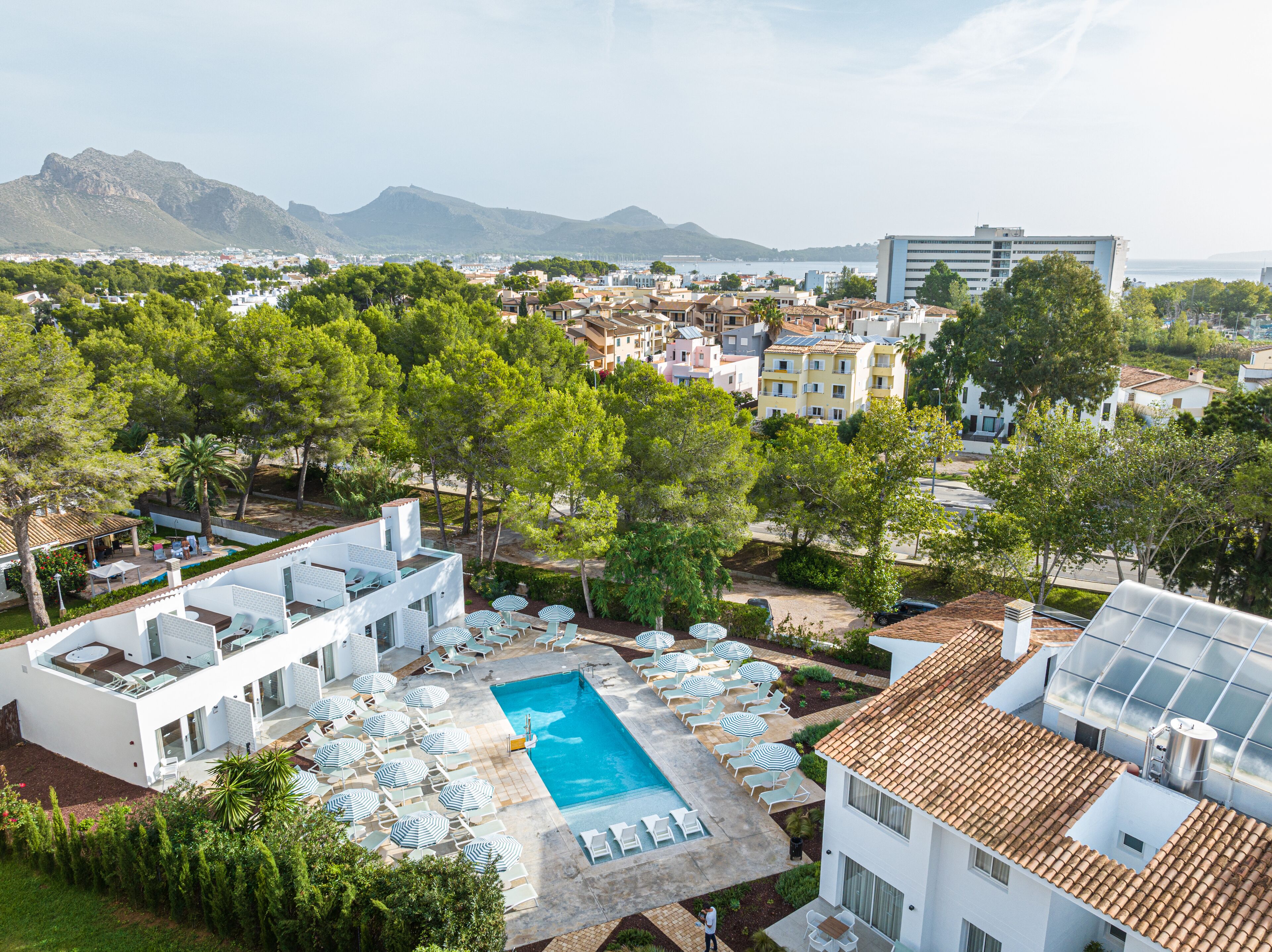 A resort with a swimming pool, lounge chairs, and a view of the city and mountains.