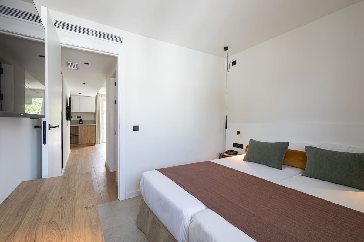 A modern hotel room with a large bed, a wooden nightstand, and a desk.