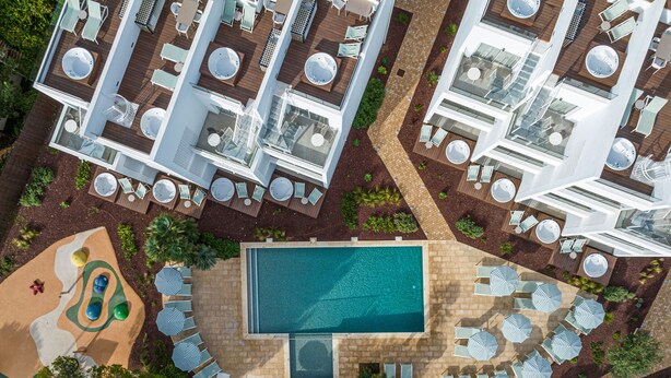 An aerial view of a resort with multiple swimming pools, sun loungers, and a children's play area.