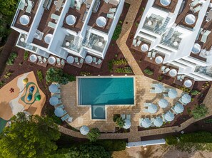 An aerial view of a resort with multiple swimming pools, sun loungers, and a children's play area. - Cabot Las Velas Apartments (Pollenca)