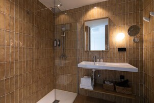 Un baño moderno con ducha de vidrio, un lavabo blanco y un espejo encima.
