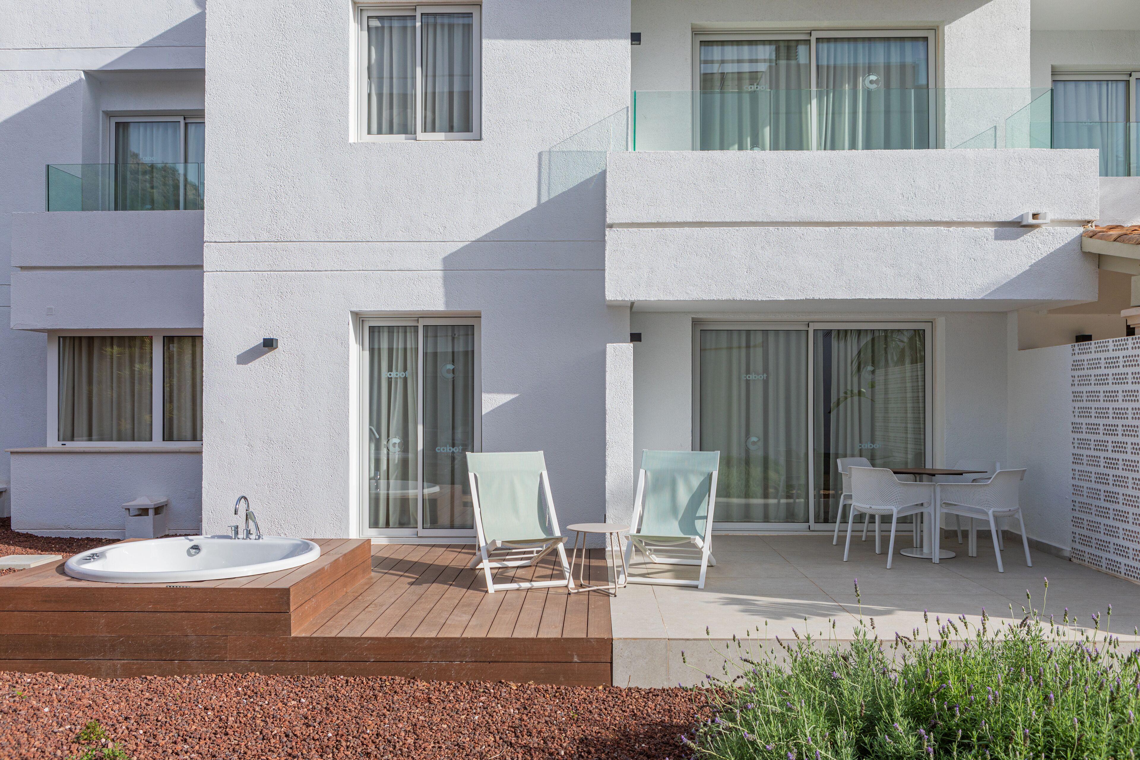 A modern building with a pool, outdoor seating, and a glass balustrade.