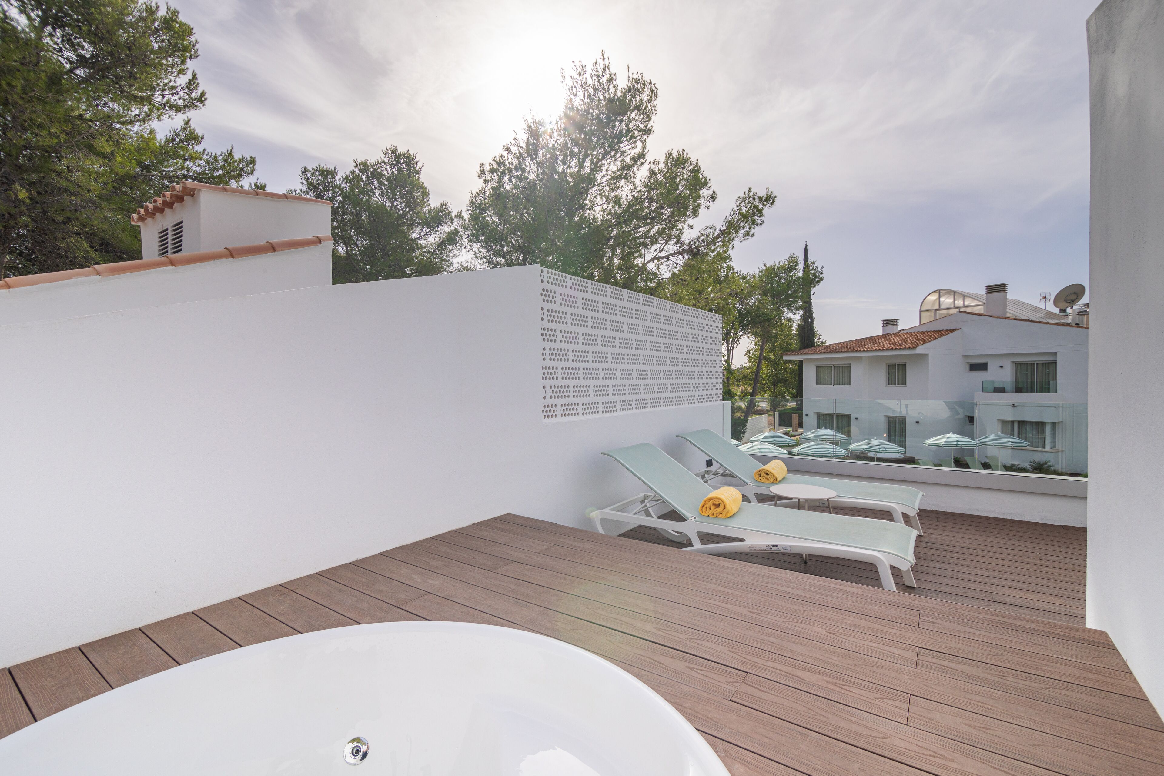 Une terrasse sur le toit équipée d’un jacuzzi, de chaises longues et d’un mur blanc orné d’une inscription.