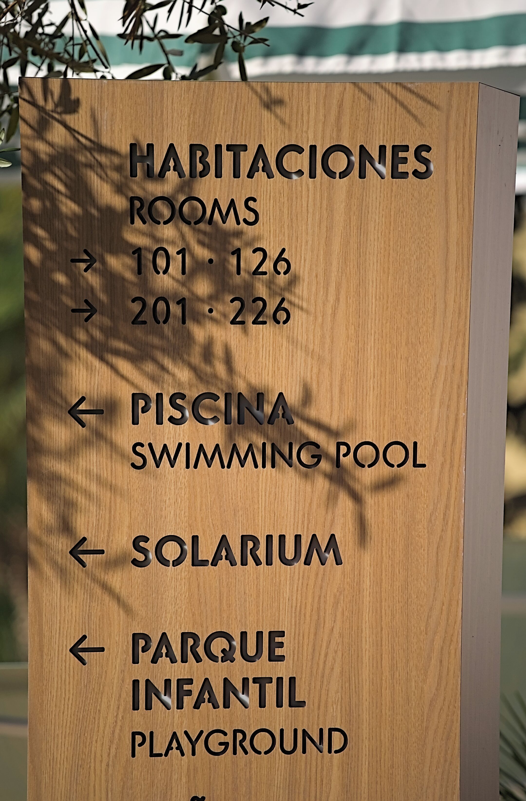 A directional sign with room numbers and amenities like a swimming pool, solarium, and playground.