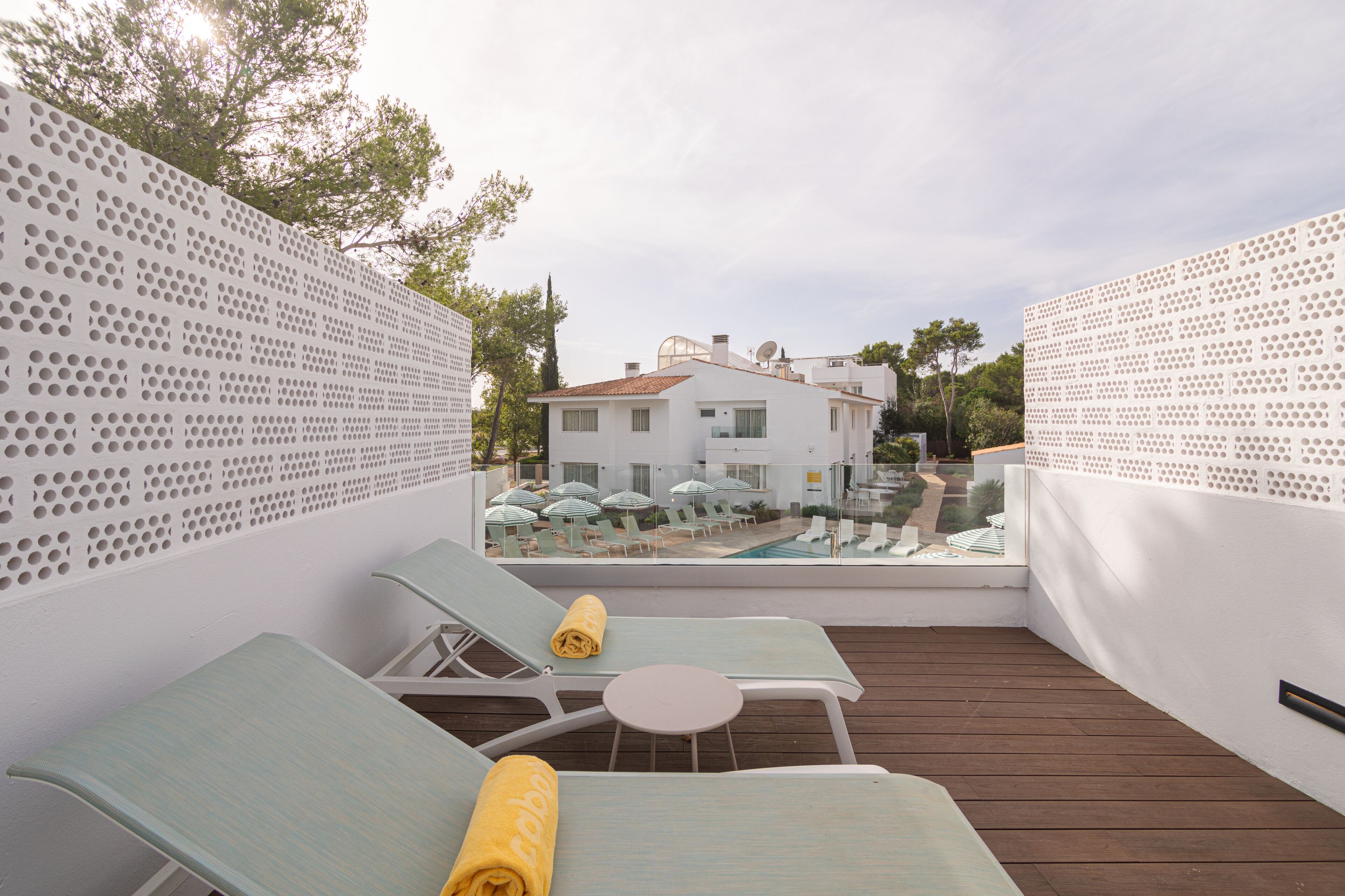 Une terrasse sur le toit, dotée de chaises longues et offrant une vue sur la piscine.