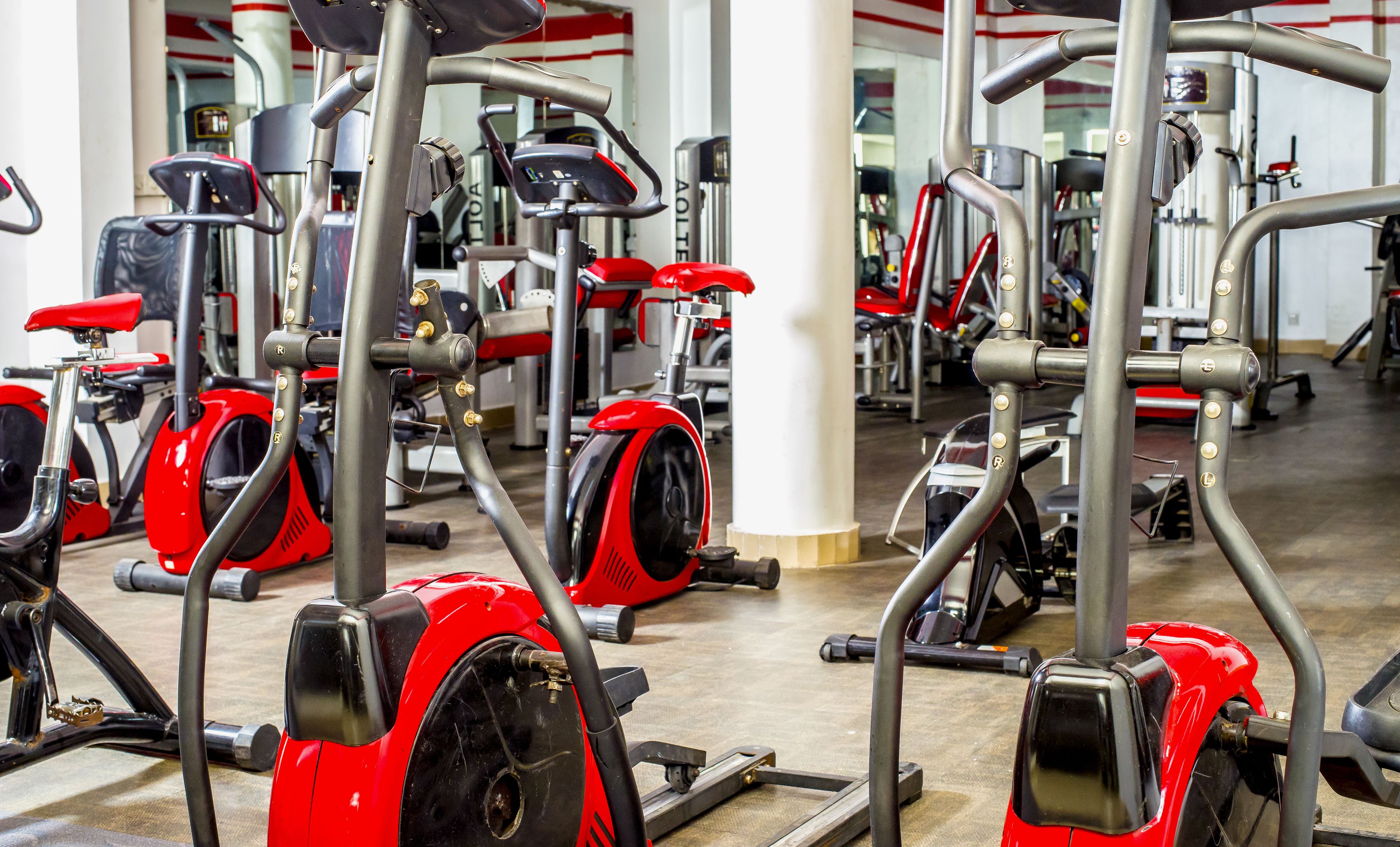 Une salle de sport équipée de divers appareils d’exercice, notamment des tapis de course et des vélos d’appartement, disposés en rangées.