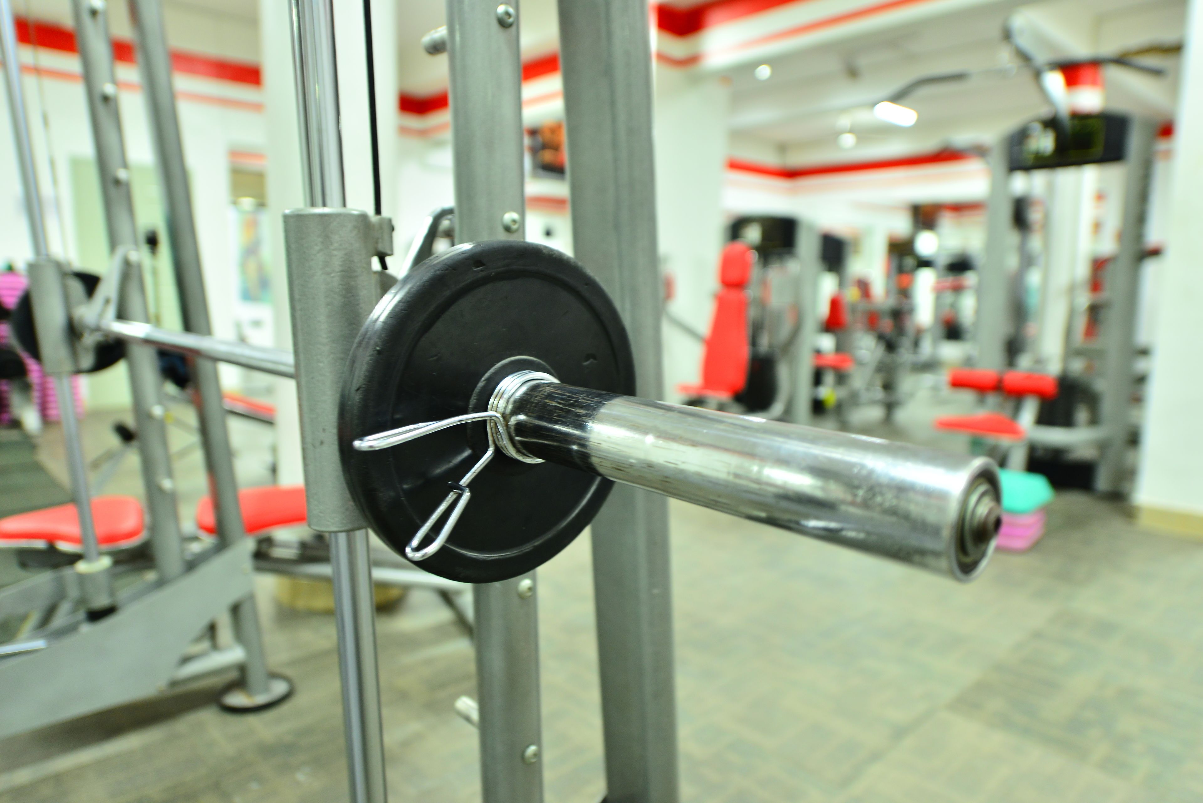 A weightlifting machine with a barbell and weights, surrounded by other gym equipment.