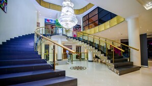 A grand staircase with a chandelier, a second staircase with patterned railings, and a modern interior design.