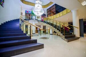 A grand staircase with a chandelier, a second staircase with patterned railings, and a modern interior design.