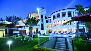 A modern hotel with a central atrium, outdoor seating, and a glass staircase.